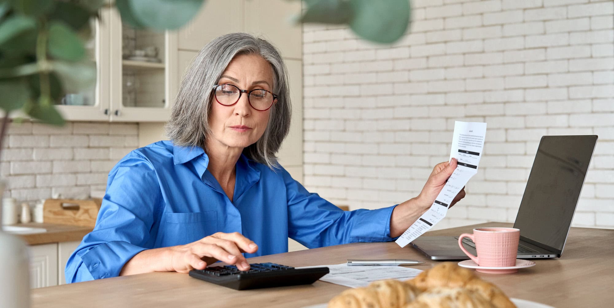Senior mid 60s aged woman calculating bank fee with computer. Occupational QROPS schemes