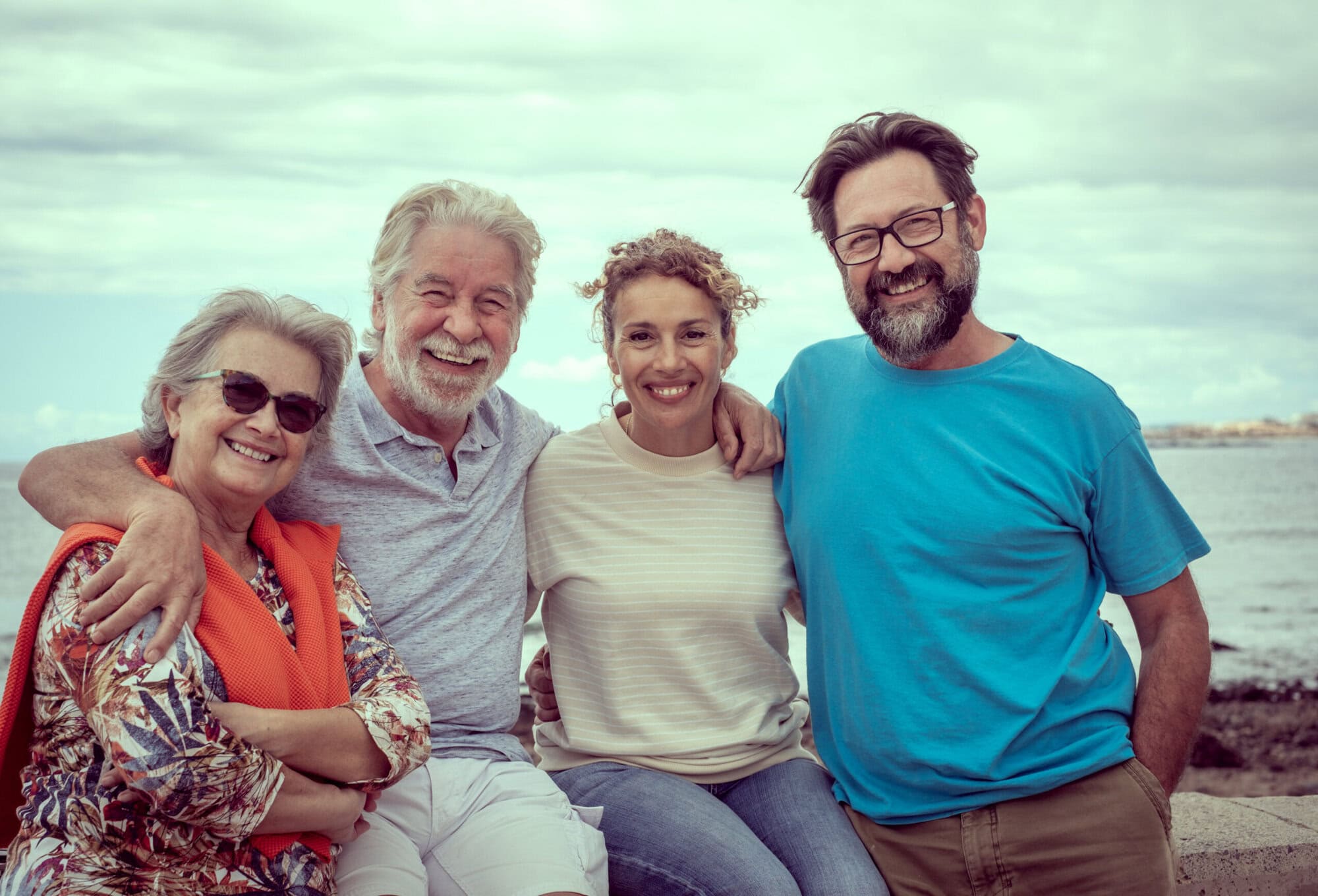 Relaxed group of multigeneration family hug with love sitting outdoor by the sea. Two married happy couple Make the right will and legal decisions to secure your beneficiaries' inheritance.
