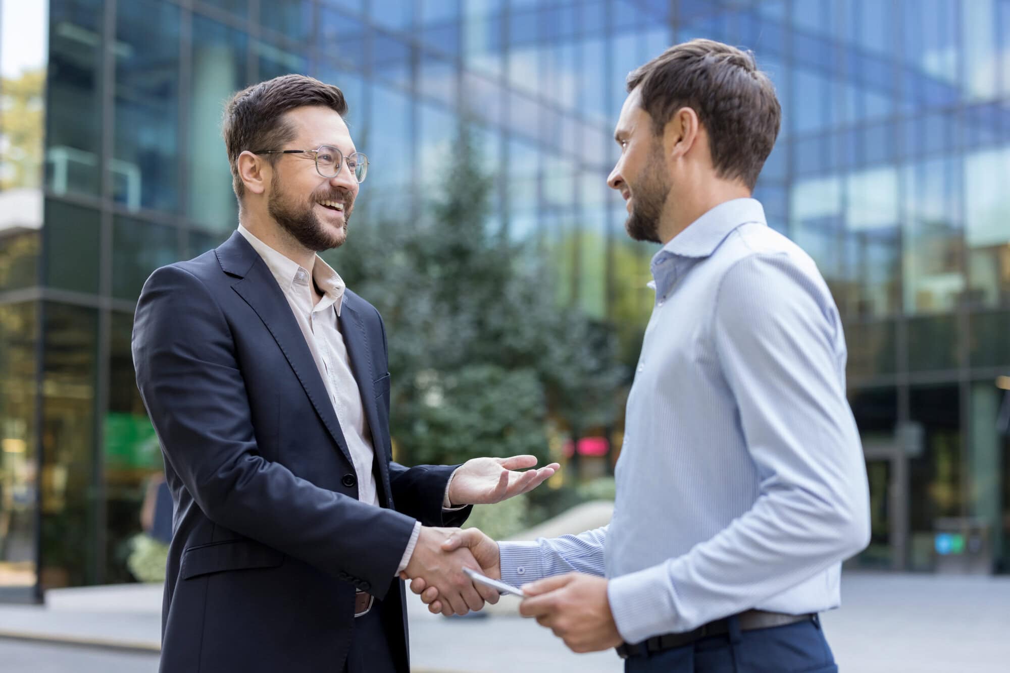 Businessmen shaking hands making a successful deal outdoors UK financial adviser