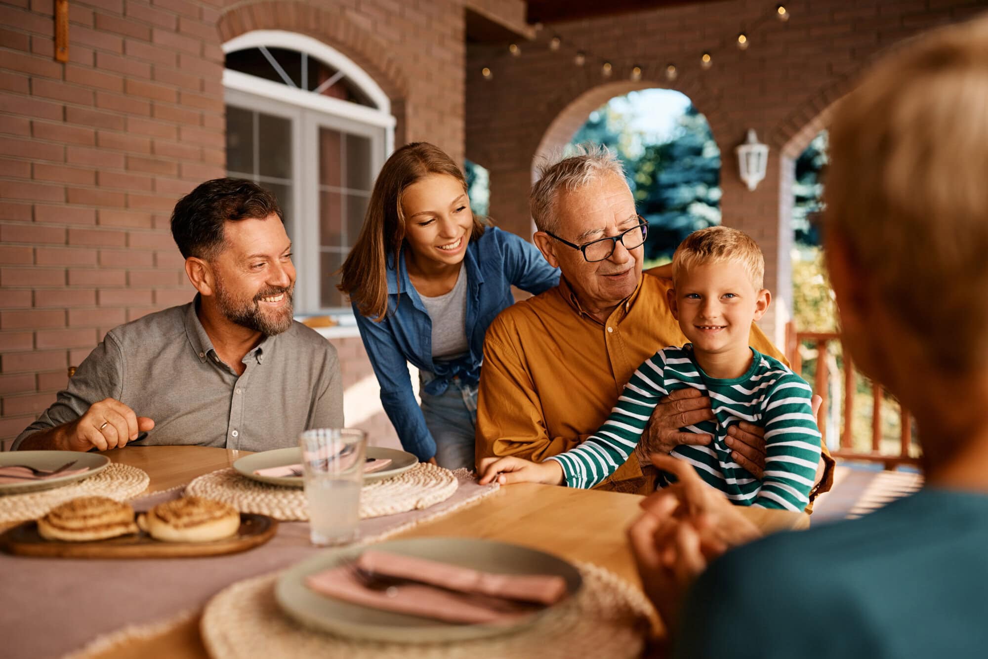 Happy multigeneration family talks while gathering for lunch at dining table on patio. uk pension inheritance tax 2027 expats